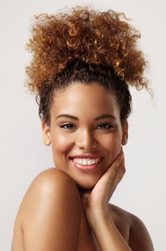 Smiling Black woman with curly, highlighted hair