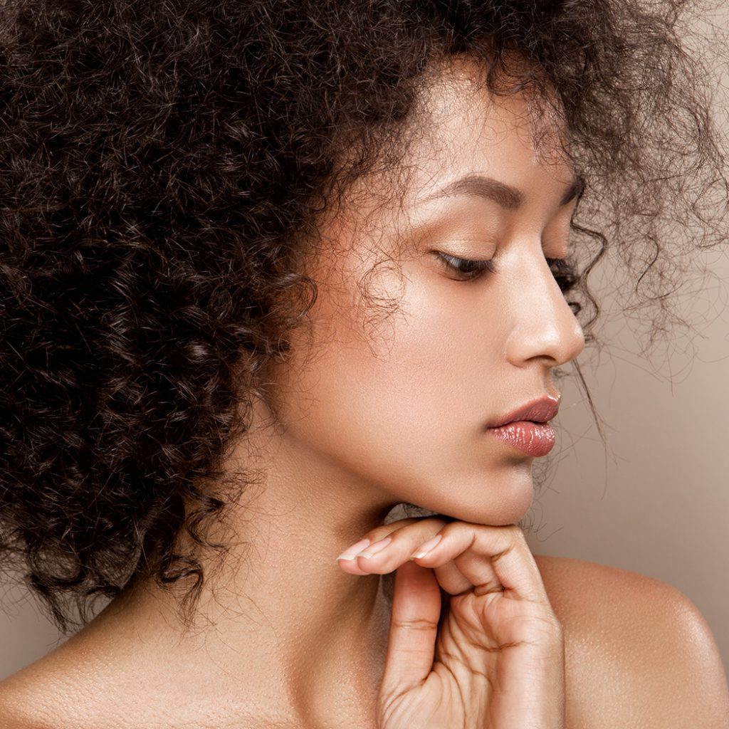 Woman with curly hair holding her chin