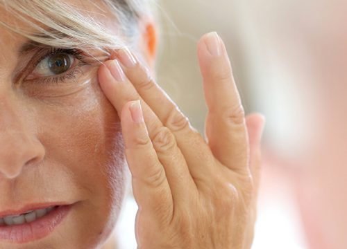 Older woman touching the fine lines and wrinkles on her face