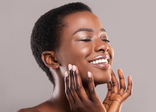 Happy woman with clear skin touching her face