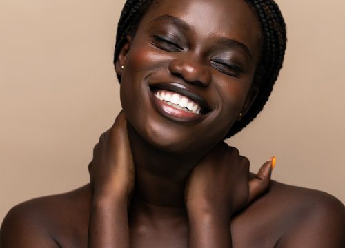 Smiling Black woman putting both hands on her neck and shoulders