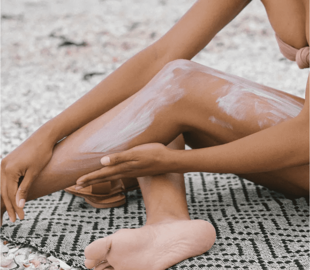 Woman rubbing sunscreen on her legs